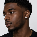 Close-up of a man wearing a diamond earring on a plain background