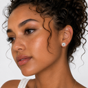 Close-up of a woman wearing a diamond earring on a neutral background